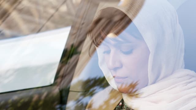 Frau mit Kopftuch sitzt in Auto. Frau mit Kopftuch sitzt in Auto.