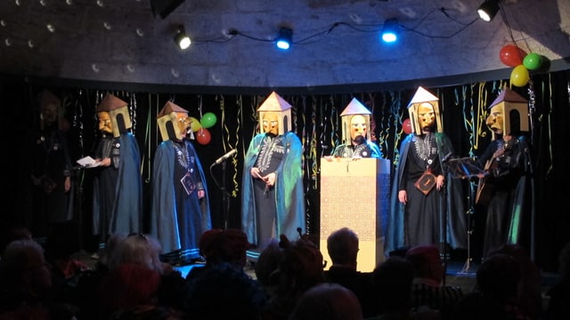 Männer in blauen Gewändern und mit Turm-Masken. Männer in blauen Gewändern und mit Turm-Masken.