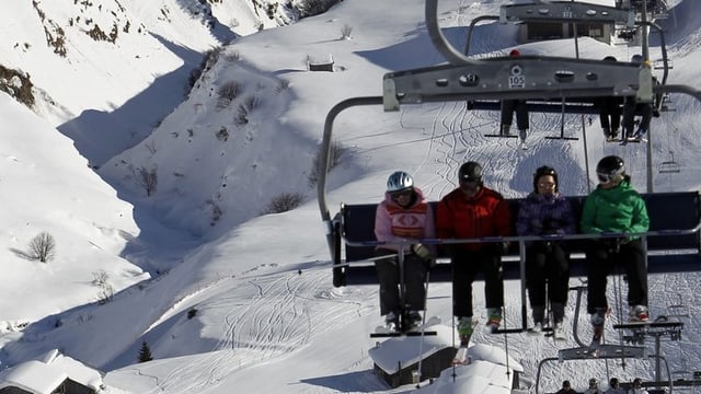 Vier Skifahrer auf einem Sessellift.