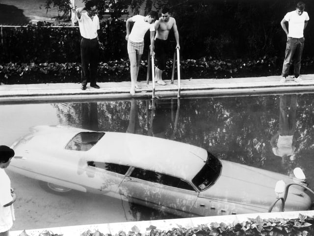 Auto am Boden eines Pools, darum stehen Menschen Auto am Boden eines Pools, darum stehen Menschen