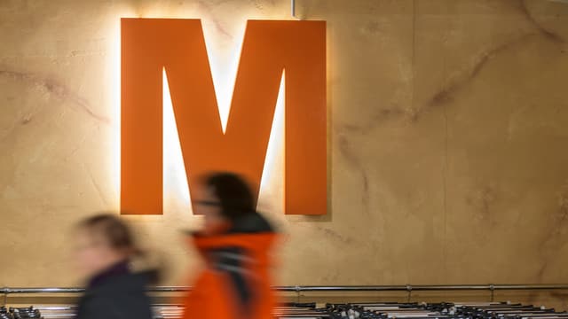 Personen gehen an einem Migros-Logo vorbei. Personen gehen an einem Migros-Logo vorbei.
