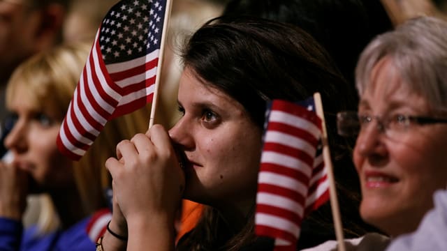Gerührte Zuschauer mit kleinen USA-Flaggen in der Hand Gerührte Zuschauer mit kleinen USA-Flaggen in der Hand