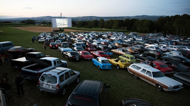 Eine Wiese mit einer Leinwand, davor viele Autos. Eine Wiese mit einer Leinwand, davor viele Autos.