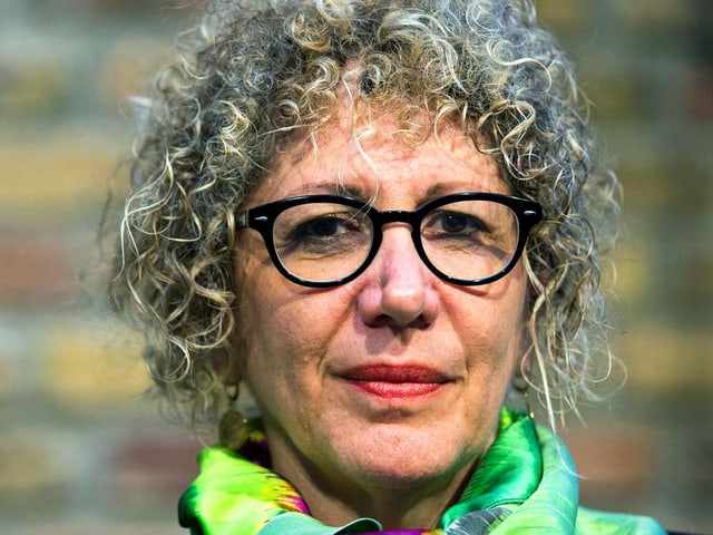 Eine Frau mit einem blonden Lockenkopf und schwarzer Brille. Eine Frau mit einem blonden Lockenkopf und schwarzer Brille.