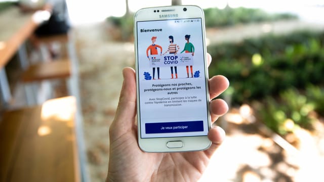 Hand mit Handy, auf dem die Tracing-App sichtbar ist Hand mit Handy, auf dem die Tracing-App sichtbar ist