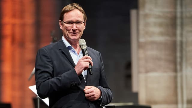 ein Mann mit einem Mikrofon, der eine Ansprache hält ein Mann mit einem Mikrofon, der eine Ansprache hält