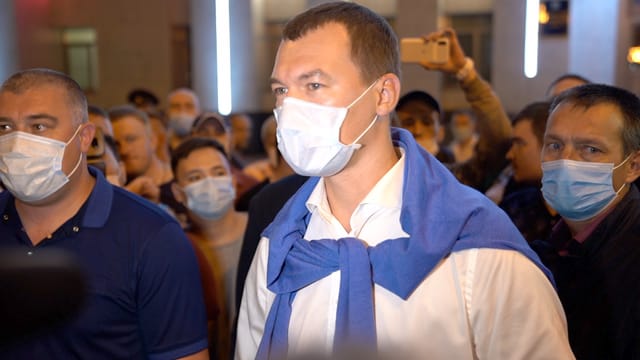 Mann mit Gesichtsmaske und einem blaumen Sweater über die Schultern gelegt. Mann mit Gesichtsmaske und einem blaumen Sweater über die Schultern gelegt.