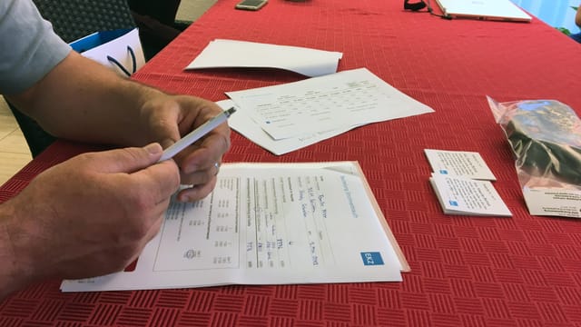 Ein Stromrechnung liegt auf einem roten Tischtuch, eine Hand mit einem Kugelschreiber Ein Stromrechnung liegt auf einem roten Tischtuch, eine Hand mit einem Kugelschreiber