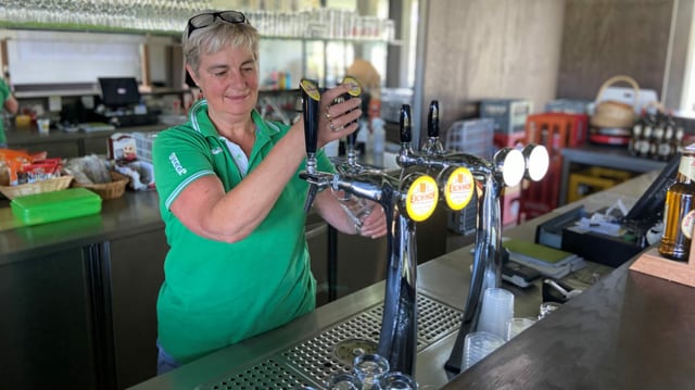 Eine Frau zapft am Tresen ein Bier. Eine Frau zapft am Tresen ein Bier.