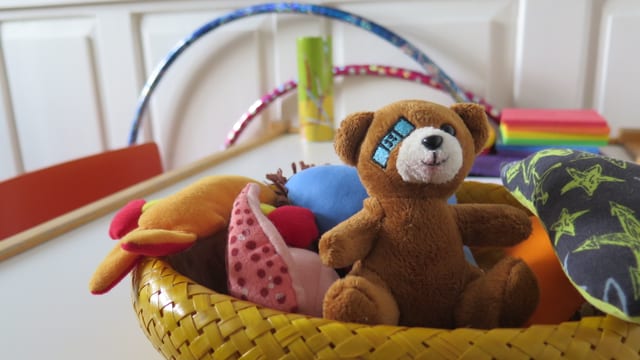 Ein kleiner Plüschbär in einem Korb von Spielsachen. Ein kleiner Plüschbär in einem Korb von Spielsachen.