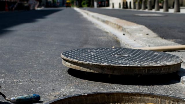 Gulli-Deckel neben offenem Gulli-Loch auf einer Strasse. Gulli-Deckel neben offenem Gulli-Loch auf einer Strasse.