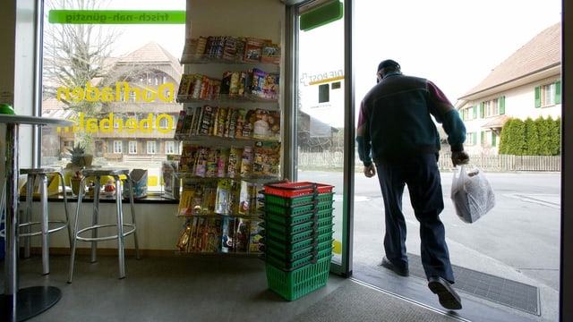 Eine Frau in einem Dorfladen, der auch Post ist Eine Frau in einem Dorfladen, der auch Post ist