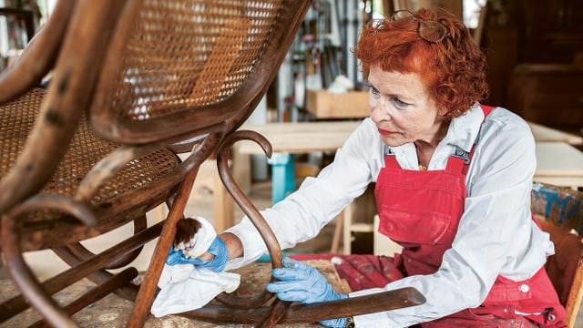 Eine Frau putzt einen Stuhl. Eine Frau putzt einen Stuhl.
