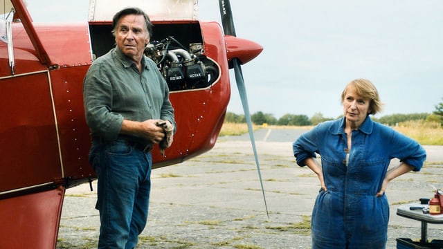 Ein Mann und eine Frau stehen neben einem Flugzeug. Ein Mann und eine Frau stehen neben einem Flugzeug.