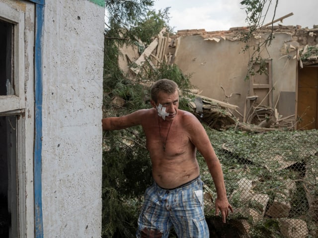 Ein Mann mit nacktem Oberkörper läuft durch die Trümmer eines Hauses.