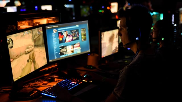 Mann vor Computerbildschirm in dunkler Umgebung Mann vor Computerbildschirm in dunkler Umgebung