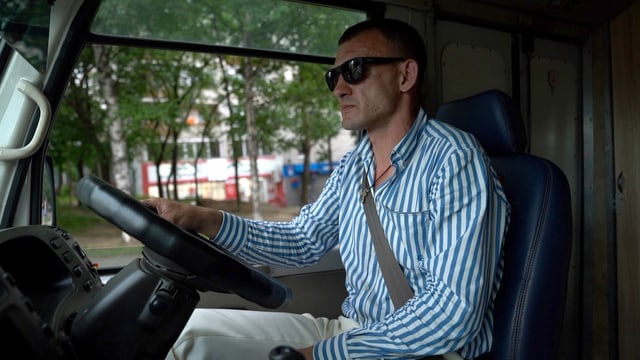Mann in Streifenhemd am Steuer von Kleinbus. Mann in Streifenhemd am Steuer von Kleinbus.