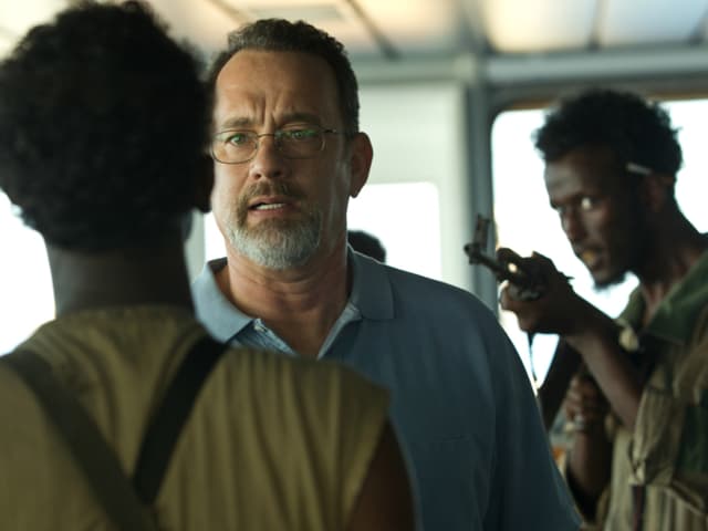 Filmszene: Tom Hanks als Schiffskapitän zwischen zwei Piraten. Einer richtet sein Gewehr auf ihn. Filmszene: Tom Hanks als Schiffskapitän zwischen zwei Piraten. Einer richtet sein Gewehr auf ihn.