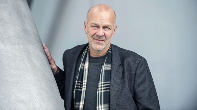 Ein Mann lehnt an einer Betonsäule. Ein Mann lehnt an einer Betonsäule.