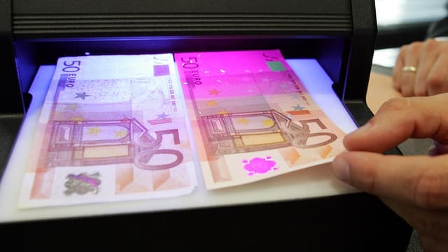 Ein falscher und ein echter 50-Euro-Schein unter einer Fluoreszenz-Leuchte. Ein falscher und ein echter 50-Euro-Schein unter einer Fluoreszenz-Leuchte.