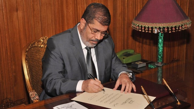 Mursi an einem Tisch sitzend. Mursi an einem Tisch sitzend.