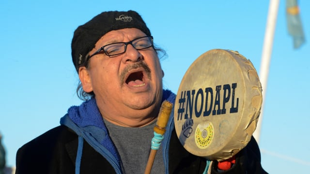 Ein Demonstrant schlägt ein Tamburin, auf dem #NODAPL steht. Ein Demonstrant schlägt ein Tamburin, auf dem #NODAPL steht.