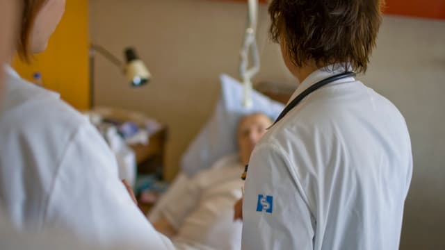 Zwei Ärzte stehen an einem Krankenbett. Zwei Ärzte stehen an einem Krankenbett.