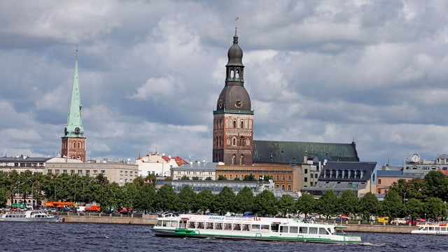 Ein Schiff fährt auf einem Fluss vor einer Kathedrale vorbei. Ein Schiff fährt auf einem Fluss vor einer Kathedrale vorbei.
