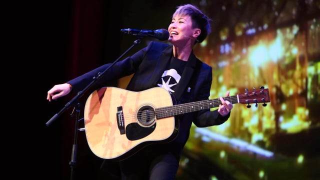Eine Frau mit Gitarre auf einer Bühne. Eine Frau mit Gitarre auf einer Bühne.
