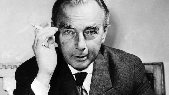 Erich Kästner in einem grauen Anzug mit Zigarette in der Hand. Erich Kästner in einem grauen Anzug mit Zigarette in der Hand.