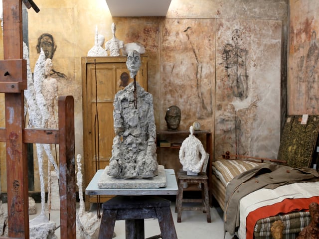 Ein Raum voller Skulpturen mit einem Schrank und einem Bett. Ein Raum voller Skulpturen mit einem Schrank und einem Bett.