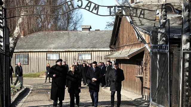 Leute unter Schriftzug «Arbeit macht frei». Leute unter Schriftzug «Arbeit macht frei».