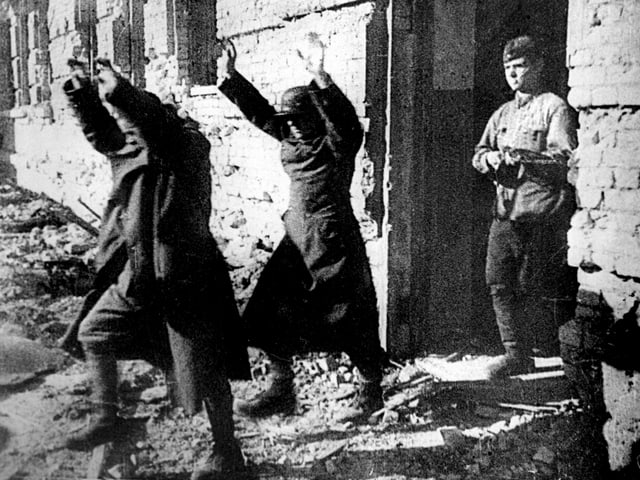 Zwei deutsche Soldaten gehen mit erhobenen Händen einem sowjetischen Soldaten voran. Zwei deutsche Soldaten gehen mit erhobenen Händen einem sowjetischen Soldaten voran.