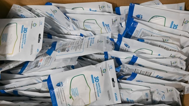 N95-Masken liegen am Eingang zum Impfzentrum einzeln verpackt in einer Kiste.