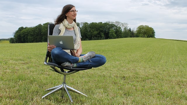Patricia Felber sitzt auf einem Bürostuhl auf einer Wiese und hat einen Laptop auf den Knien. Patricia Felber sitzt auf einem Bürostuhl auf einer Wiese und hat einen Laptop auf den Knien.
