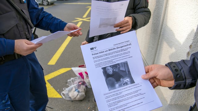 Polizisten verteilen Zeugenaufrufplakate Polizisten verteilen Zeugenaufrufplakate