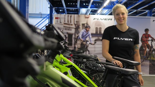 Eine Frau steht in einer Reihe mit Elektrovelos. Eine Frau steht in einer Reihe mit Elektrovelos.