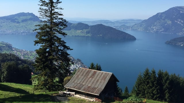 Blick über eine Hütte zum blauen Vierwaldstättersee, darüber ein wolkenloser Himmel. Blick über eine Hütte zum blauen Vierwaldstättersee, darüber ein wolkenloser Himmel.