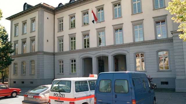 Gebäude aus Stein, davor Polizeiautos. Gebäude aus Stein, davor Polizeiautos.