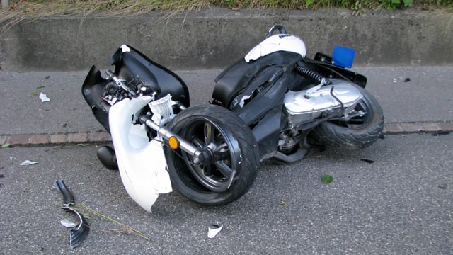 Ein kaputter Roller liegt umgekippt am Strassenrand Ein kaputter Roller liegt umgekippt am Strassenrand