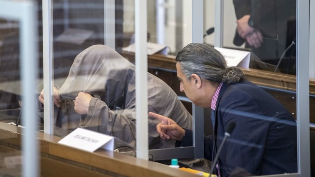 Angeklagter versteckt sein Gesicht mit seiner Jacke im Gerichtssaal. Angeklagter versteckt sein Gesicht mit seiner Jacke im Gerichtssaal.