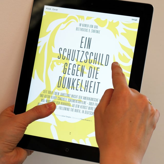 Ein Finger fährt über ein Tablet-Bildschirm, auf dem gross geschrieben steht «Ein Schutzschild gegen die Dunkelheit». Ein Finger fährt über ein Tablet-Bildschirm, auf dem gross geschrieben steht «Ein Schutzschild gegen die Dunkelheit».