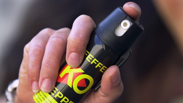 Hand hält einen Pfefferspray und will abdrücken. Hand hält einen Pfefferspray und will abdrücken.