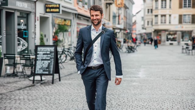 Mann in Anzug geht lachend durch Winterthurer Altstadt Mann in Anzug geht lachend durch Winterthurer Altstadt