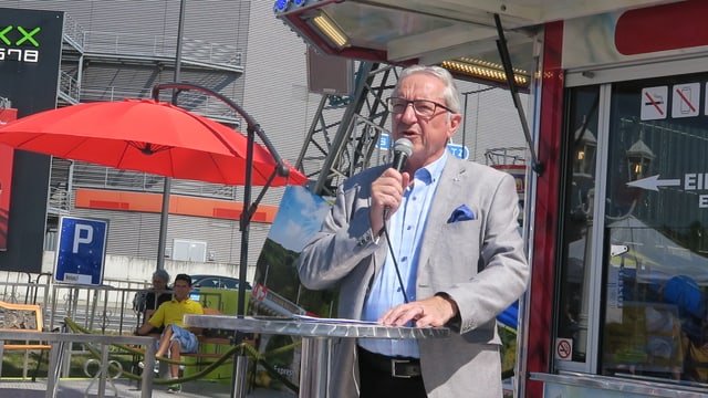 Ein Mann mit Brille, der in ein Mikrofon spricht. Ein Mann mit Brille, der in ein Mikrofon spricht.