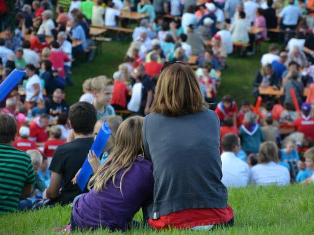 Frau und Kind sitzen aneinandergelehnt im Gras.