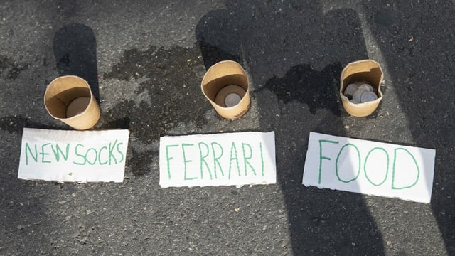 Die Becher sind mit «Neue Socken», «Ferrari» und «Essen» angeschrieben. Die Becher sind mit «Neue Socken», «Ferrari» und «Essen» angeschrieben.