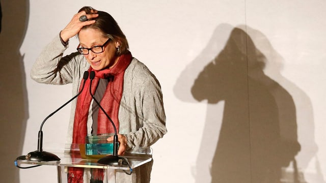 Lydia Davis an einem Stehpult im Rampenlicht. Lydia Davis an einem Stehpult im Rampenlicht.