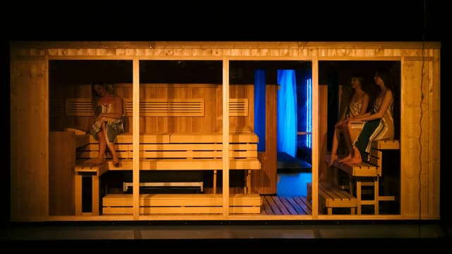 Eine Sauna, vorne offen und der Zuschauer blickt hinein. Darin sitzen drei Frauen mit Tüchern bedeckt. Eine Sauna, vorne offen und der Zuschauer blickt hinein. Darin sitzen drei Frauen mit Tüchern bedeckt.