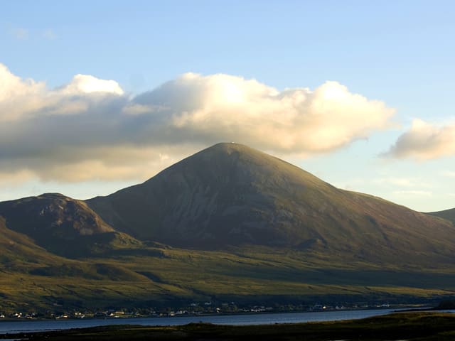 Der Berg Croagh Patrick von weitem, wie er eingebettet von grünen Weisen vor einem See liegt. Der Berg Croagh Patrick von weitem, wie er eingebettet von grünen Weisen vor einem See liegt.